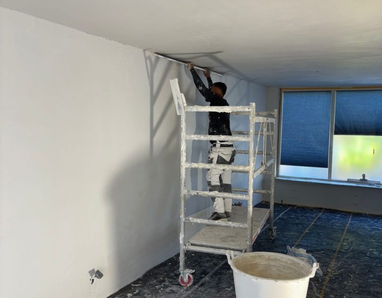 een werknemer die een muur aan het stuken is. Glad stucwerk uitgevoerd door Hoeksche Waard Bouwservice in Zuid-Holland